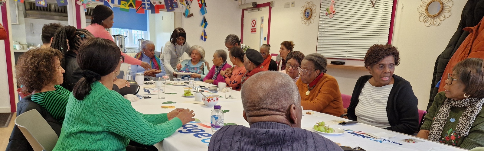 A large group of older Caribbean men and women gathered around a table