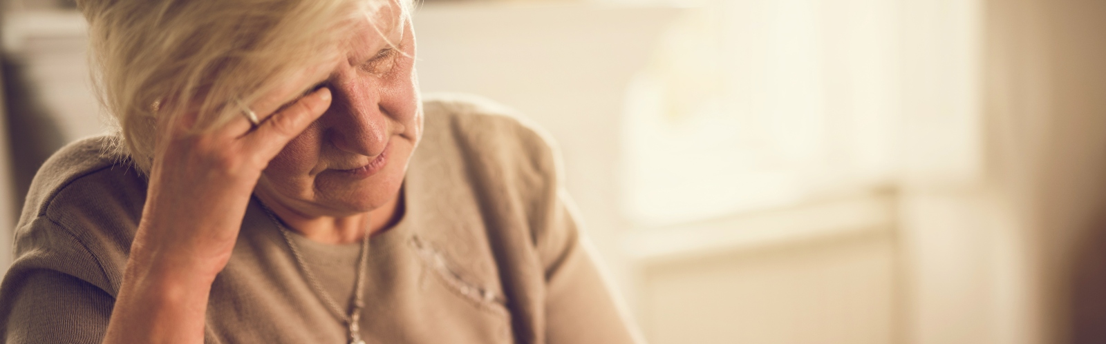 A woman in her 60s, taking medication and looking pained